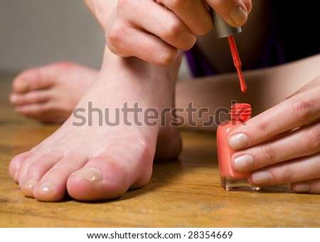 Woman applying nail polish on toe nails
