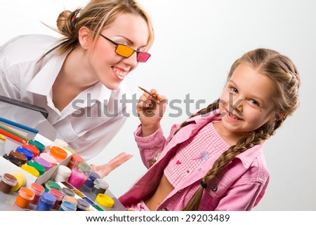 Adorable little girl painting mother\'s glasses
