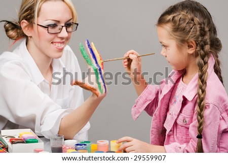 Little girl playing with mom, painting her fingers