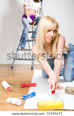 Young pretty girls applying wallpapers on walls