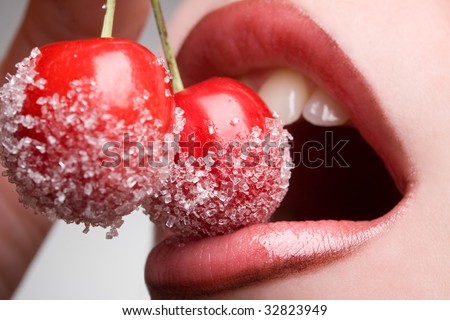 young woman's mouth with red cherries covered with sugar