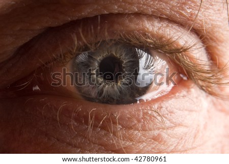Widely open elderly man\'s eye closeup