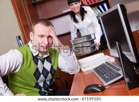 Young man in casual clothes and his colleague loaded with folders