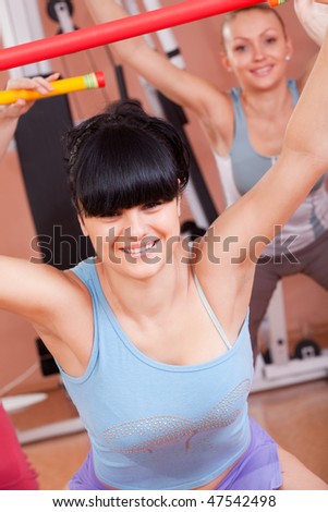 Young women in gym doing exercises with fitness sticks