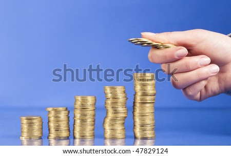 The main thing on top of money savings is their safety. Steps up of golden coins and hand is counting coins isolated on blue