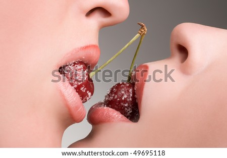 Female lovers enjoying erotic act with red cherries