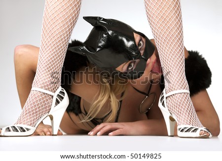 Hot beautiful model in latex black cat costume lick a leg of her dominatrix