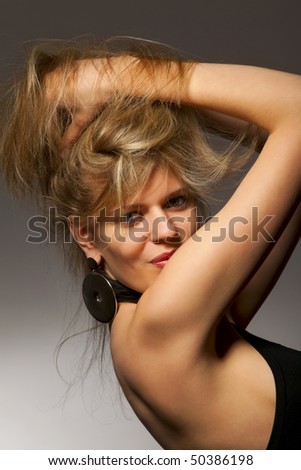 Passionate woman in evening dress fluffing up dark hair, both hands risen behind head