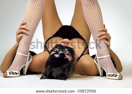Hot beautiful model in latex black cat costume between legs of her dominatrix