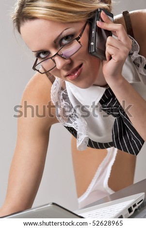 Beautiful sexy secretary with mobile wearing very short skirt pretending to work on laptop