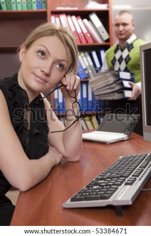 Thoughtful woman leaning on desktop with colleague on background