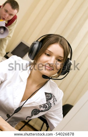 young beautiful woman with headset at workplace and her boss shouting  into a megaphone