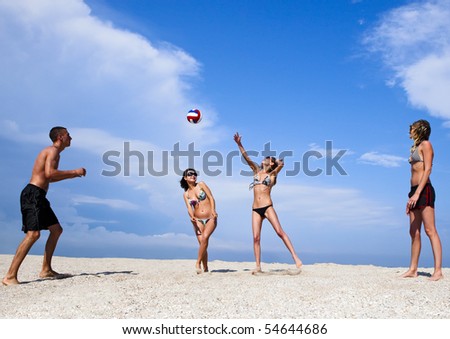 Image of cheerful young people on the beach playing volleyball. Great summer holidays.