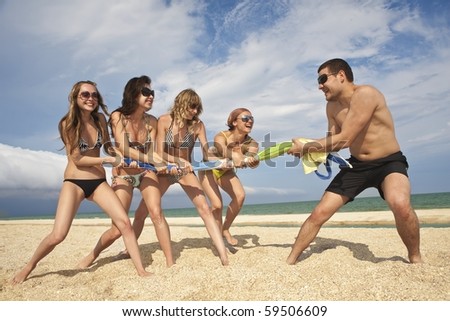 Tug-of-war between girls and guy on the beach