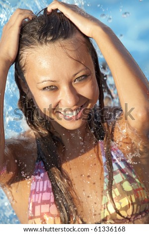 Beautiful woman bathes in pool under water splashes
