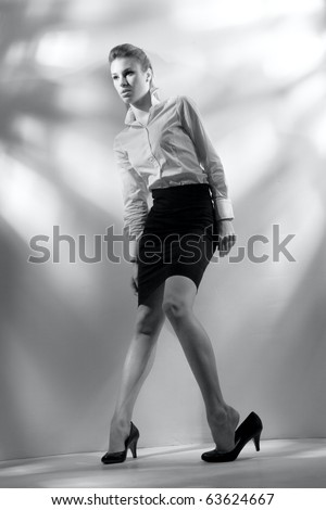 Black and white portrait of beautiful woman in business suit, leaning on the wall