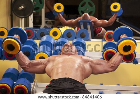 Fitness - powerful muscular man with a bar weights in hands training