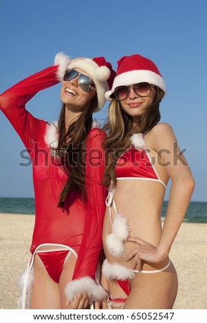 Two happy girls in Santa Clause suit having fun on the beach