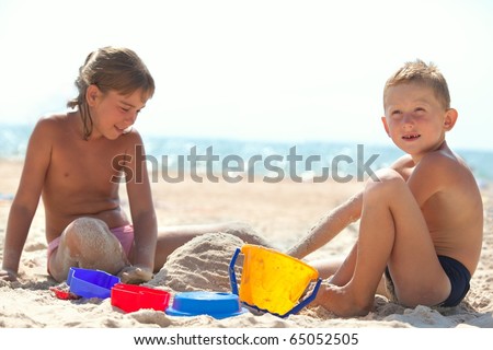 Sister and brother building sand castle on beach (Focus is on the boy)
