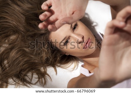 The young girl lying and pulling hands upwards is isolated on a white background (Focus on  face)