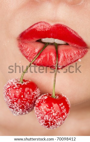 Young woman\'s mouth with red cherries covered with sugar