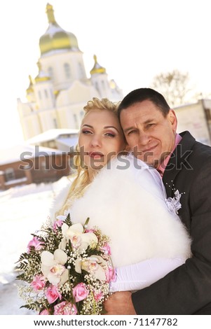 Beautiful bride and groom on church background in winter time