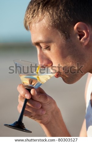 Portrait of guy drinking cocktail on beach