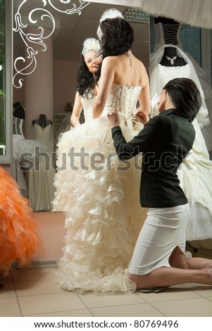 Women making adjustment to wedding gown in professional fashion designer studio