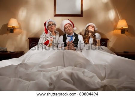 Manager with two his subordinates reading a business plan sitting in bed on New Year\'s night