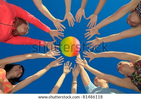 Several hands reaching out together in a circle for volley ball against blue sky