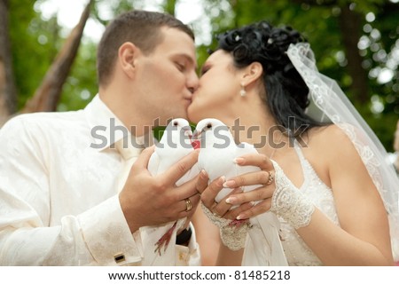 Beautiful newlyweds  kissing holding white doves in hands