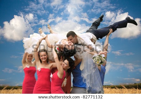 A happy groom and bride  tossed into sky by a group of friends