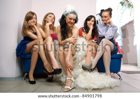 Bride sitting with envious girlfriend in professional fashion designer studio