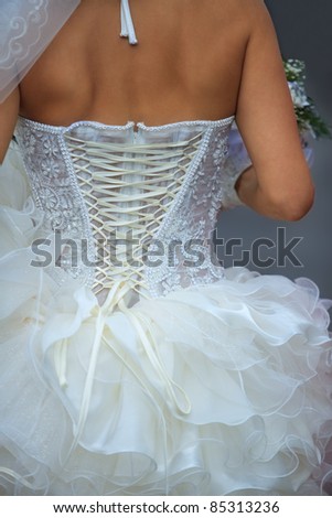 A young woman in white dress laced up from the back.