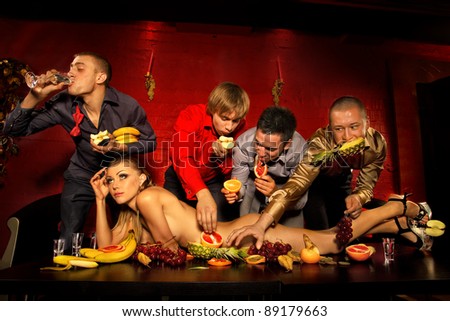 Four guys having fun with woman decorated  by fruits