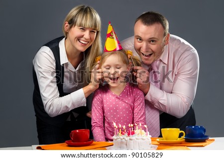 Happy family pulling on their daughter\'s ears in her birthday