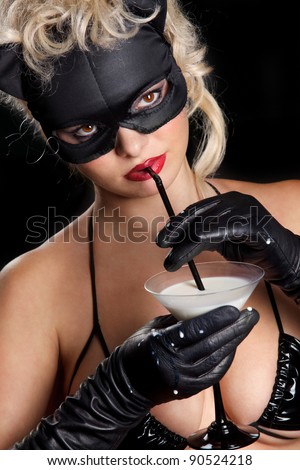 Portrait of the blonde model wearing black cat, licking - drinking milk from the martini glass