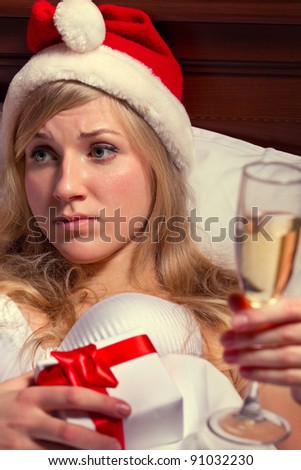 Young woman in Santa\'s hats  with glass of champagne lying on bed remain all alone