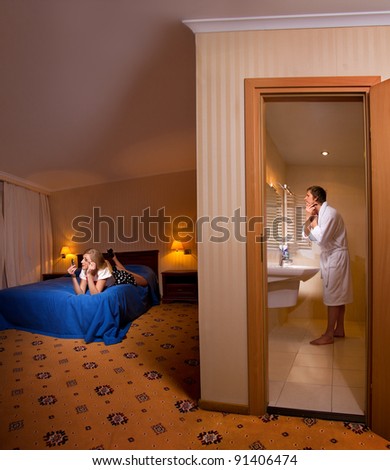 Evening preparing of family for going out. Man shaving in the bathroom and his wife making up on bed