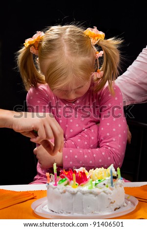 Little sad girl sitting in front of birthday cake