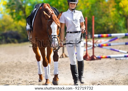 Image of  female jockey with purebred horse outdoors