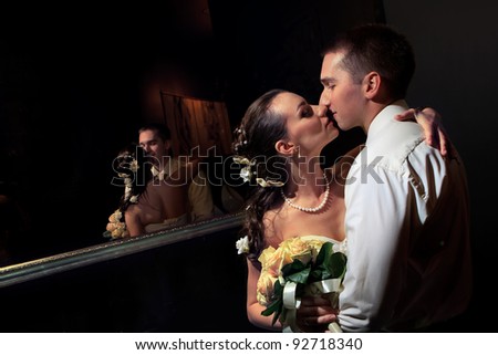 Wedding shot of bride and groom kissing next to mirror