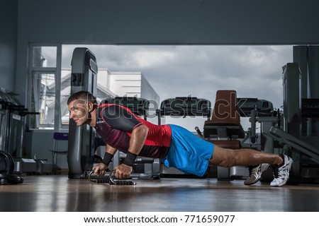 Fitness training. Man doing push ups exercise using Push-up Bars in  gym