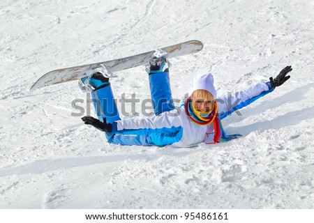 Young laughing woman with snowboard lying in the snow