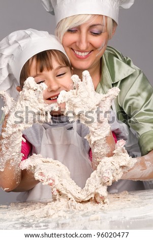 Happy, blond caucasian mother and daughter preparing dough and having fun