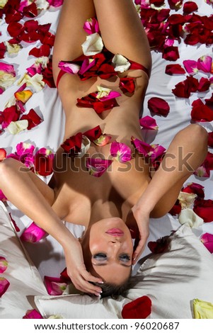 Woman lying in bed covered by Flower Petals
