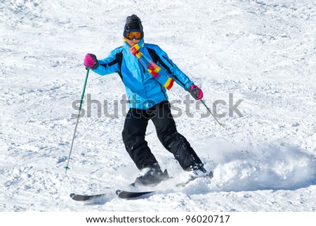 Young male skier turning in powder snow; blue jacket; black pant; horizontal orientation