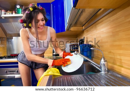 Side view of happy smiling young woman enjoying washing dishes in kitchen