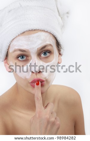 Beautiful young woman in towel doing cosmetic mask on her face