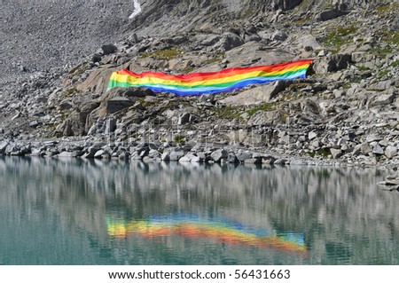 Peace flag dropped in mountain reflected in a lake, Adamello Italy